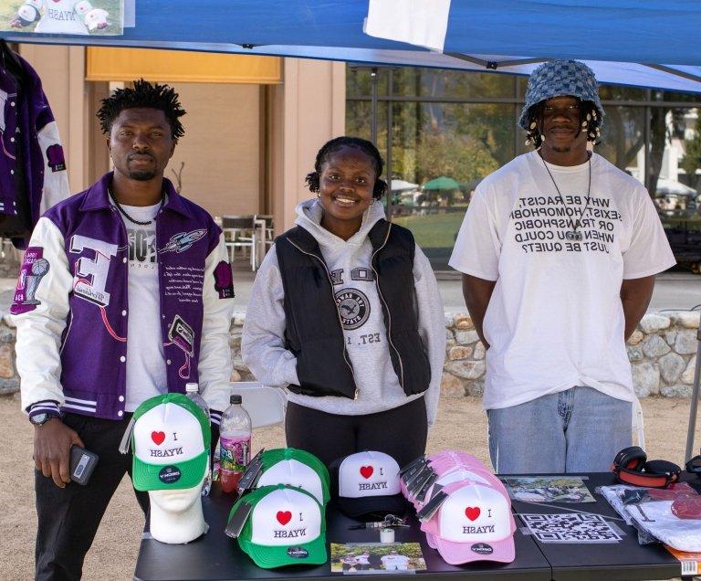 three vendors at the PZ Black Flea market pose by their stall 